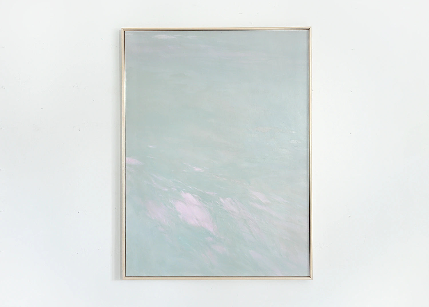 Framed abstract artwork with a light green and pink color scheme on a white wall.